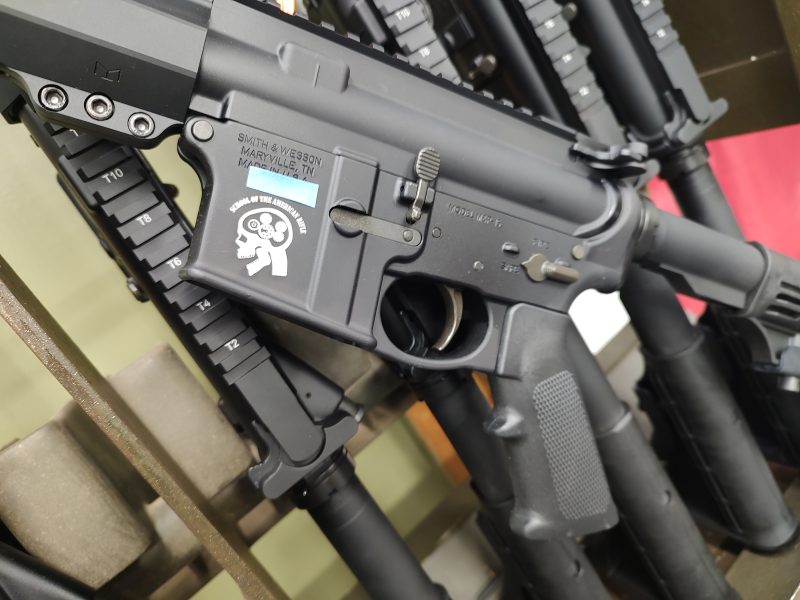 Close-up of a Smith & Wesson M&P Sport 3 rifle, featuring a visible safety selector and manufacturer markings. Other rifles are lined up in the background. RAFFLE TICKET - SOTAR Secret Shopper available for this model.