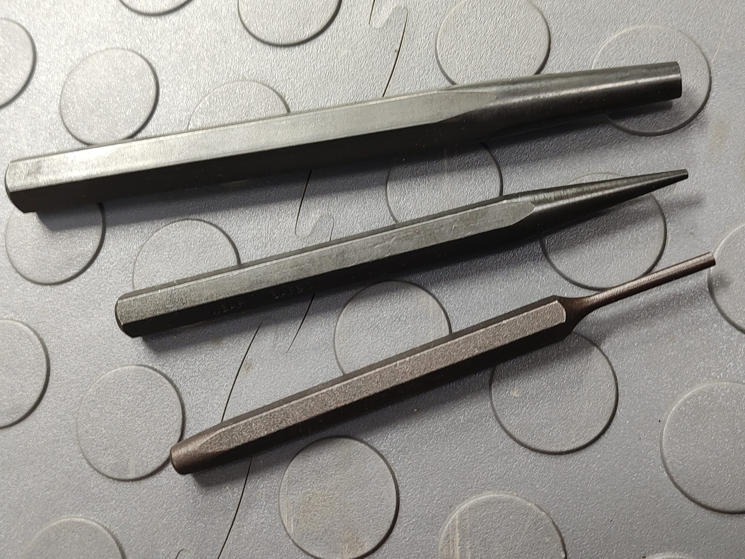The SOTAR Enhanced AR15 Extractor is displayed on a textured, circular-patterned gray surface.