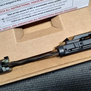 The LAW Tactical ARIC - C Model, featuring an attached spring assembly, is placed inside a cardboard box with partially visible instructions in the background.