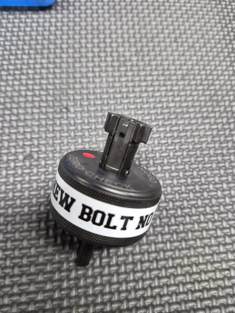 A black plastic SOTAR AR15 NEW Bolt Support Ring NOGO Gauge with a white "NEW BOLT NO" label rests on a textured gray surface.