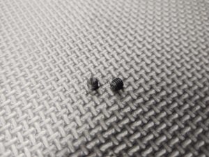 A pair of 10-32 Knurled Tip Gas Block Set Screws on a metal surface.
