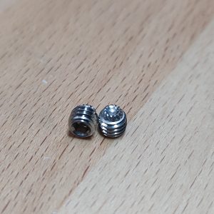 Two 10-32 "18-8 Stainless Steel" Knurled Tip Gas Block set screws on a wooden surface, one larger with ridges and the other smaller with a rounded top.
