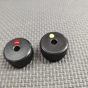 Two small black knobs with colored indicators (red and yellow) on a textured grey surface. SOTAR AR15 Bolt Tail Gauge Set - BACKORDER