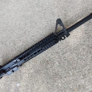 A BCM® COMPLETE 16" CHF Mid Length Complete Upper Receiver Group w/ MCMR-9 Handguard - New Old Stock - Minor Handling Marks with a handguard and front sight resting on a concrete surface.