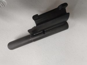 Close-up of an HK91 and Clones M-LOK Handguard, a black metal cylindrical object, resting on a light gray surface, showcasing its grooved slot and central hole.