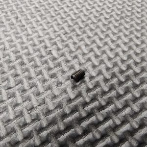 A 4-40 Set Screw lies on a grey textured surface with a grid-like pattern.