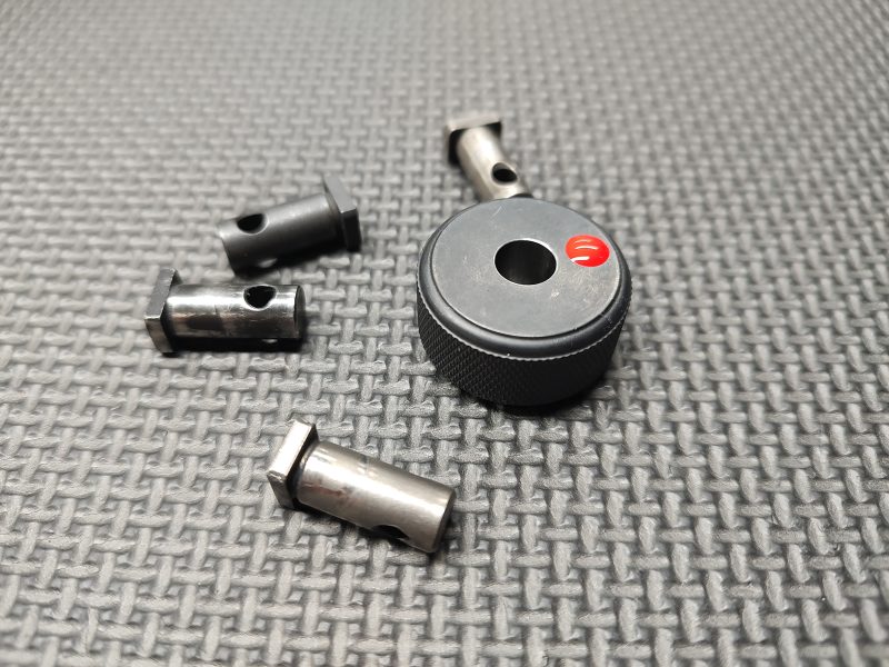 A SOTAR AR15 Cam Pin Field Gauge (Reject Gauge Only) and four metal components are placed on a textured gray surface.