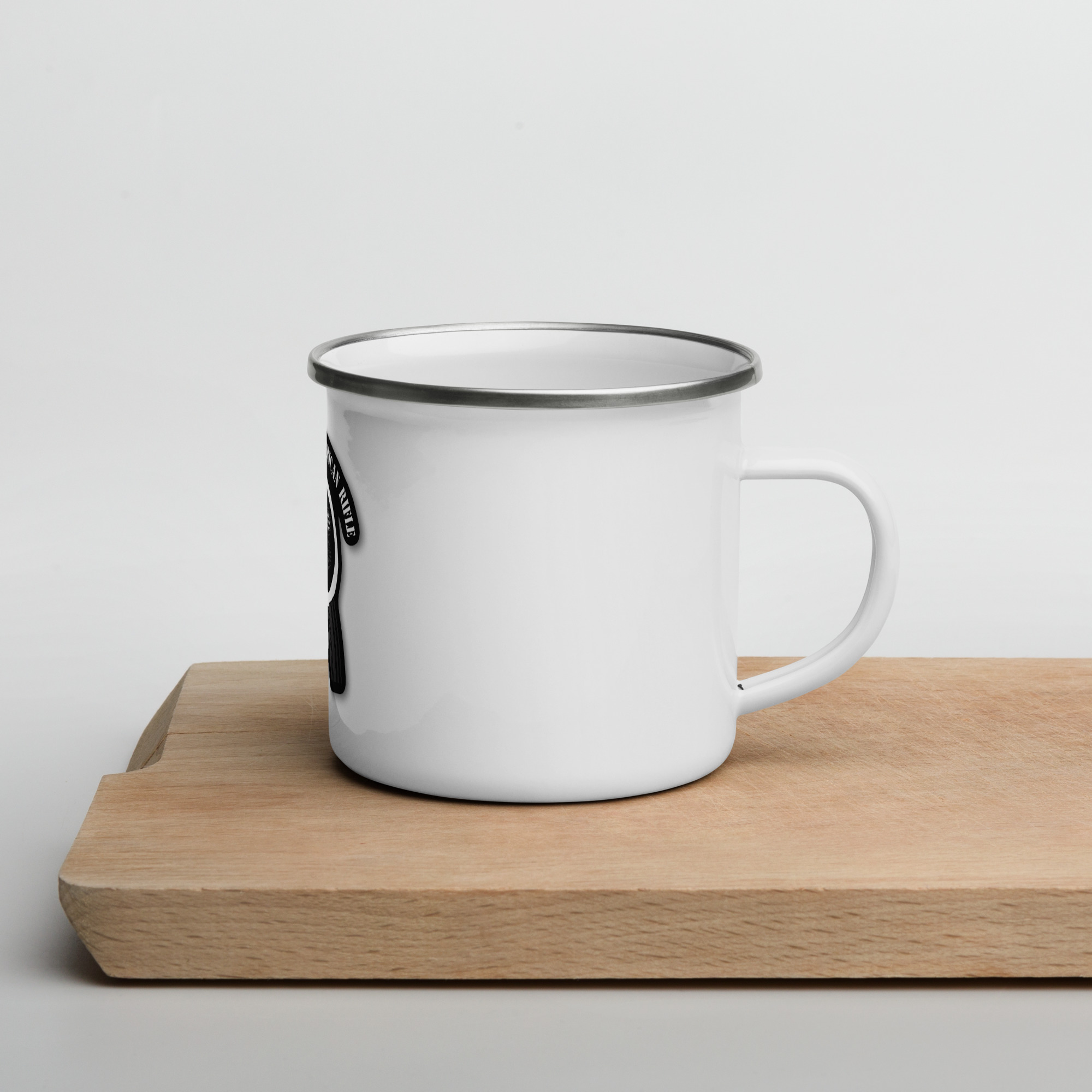 A SOTAR enamel mug sitting on a cutting board.