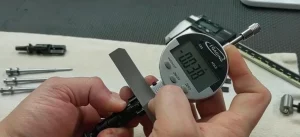 A person is using a digital caliper to measure a screw.